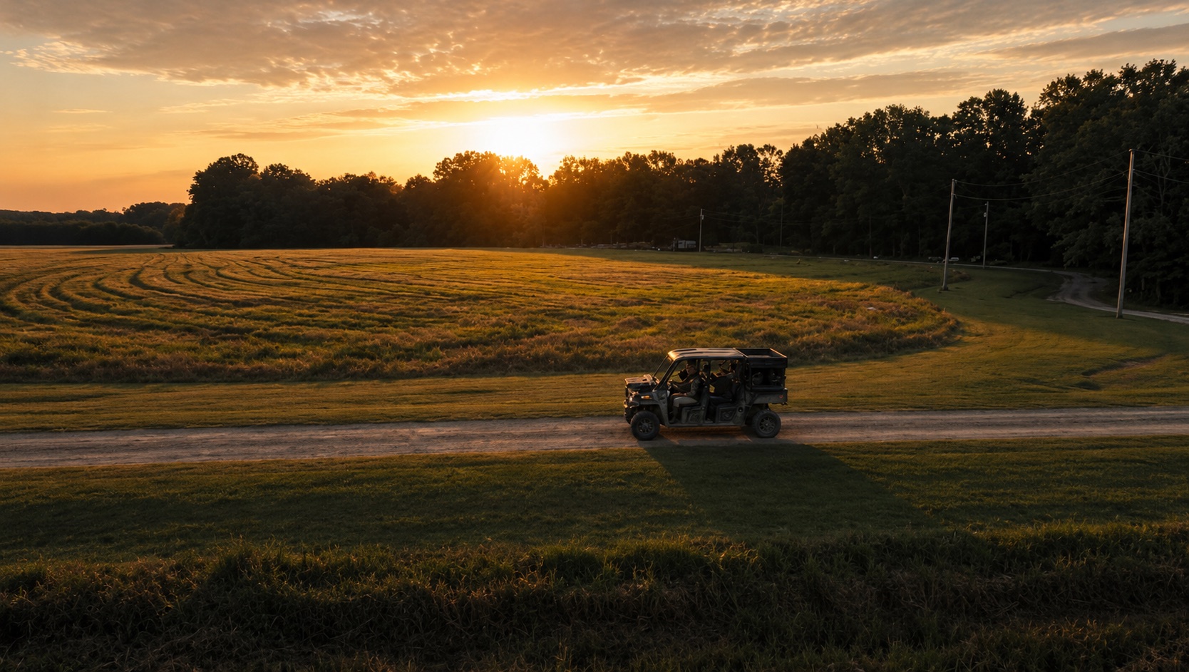 Aerial view of a utility vehicle crossing a field at sunset