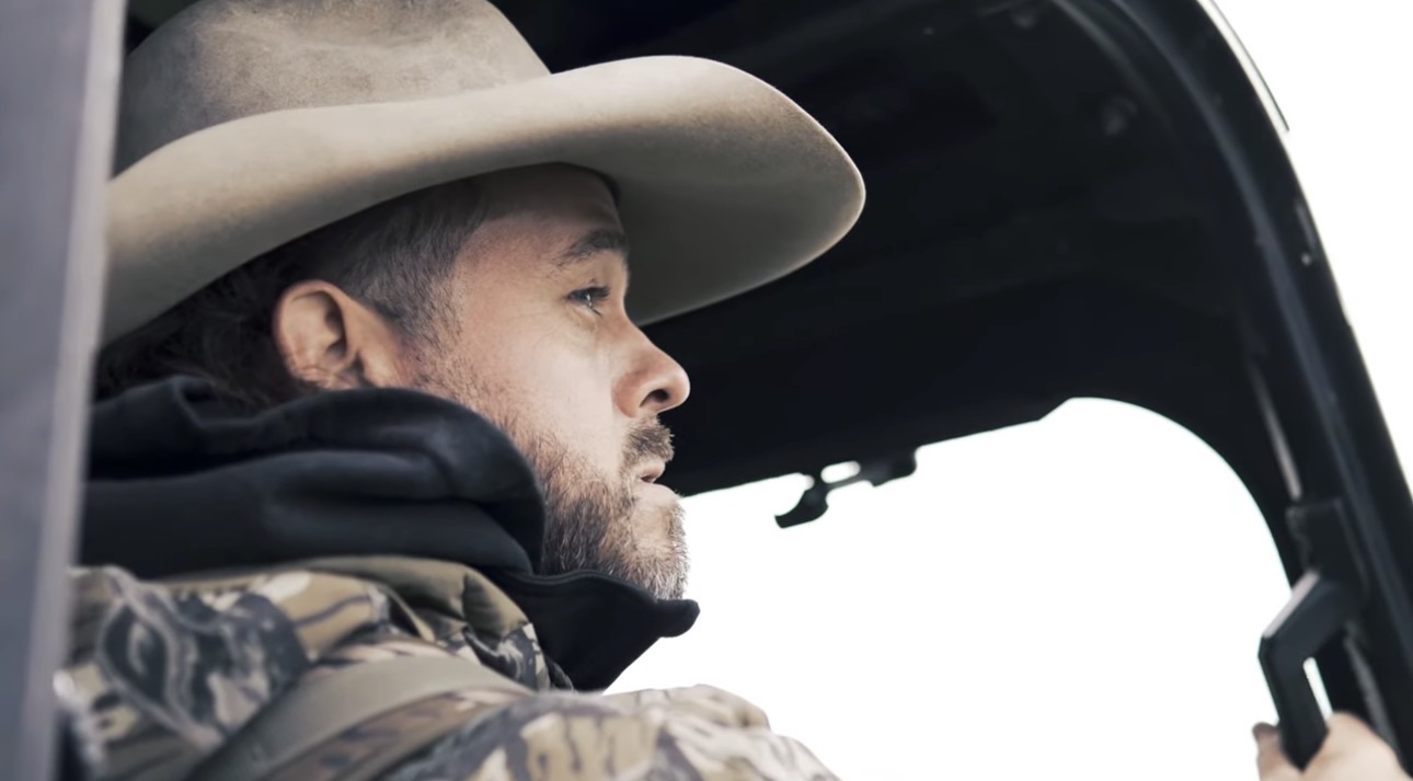 Outdoorsman wearing a cowboy hat inside a vehicle