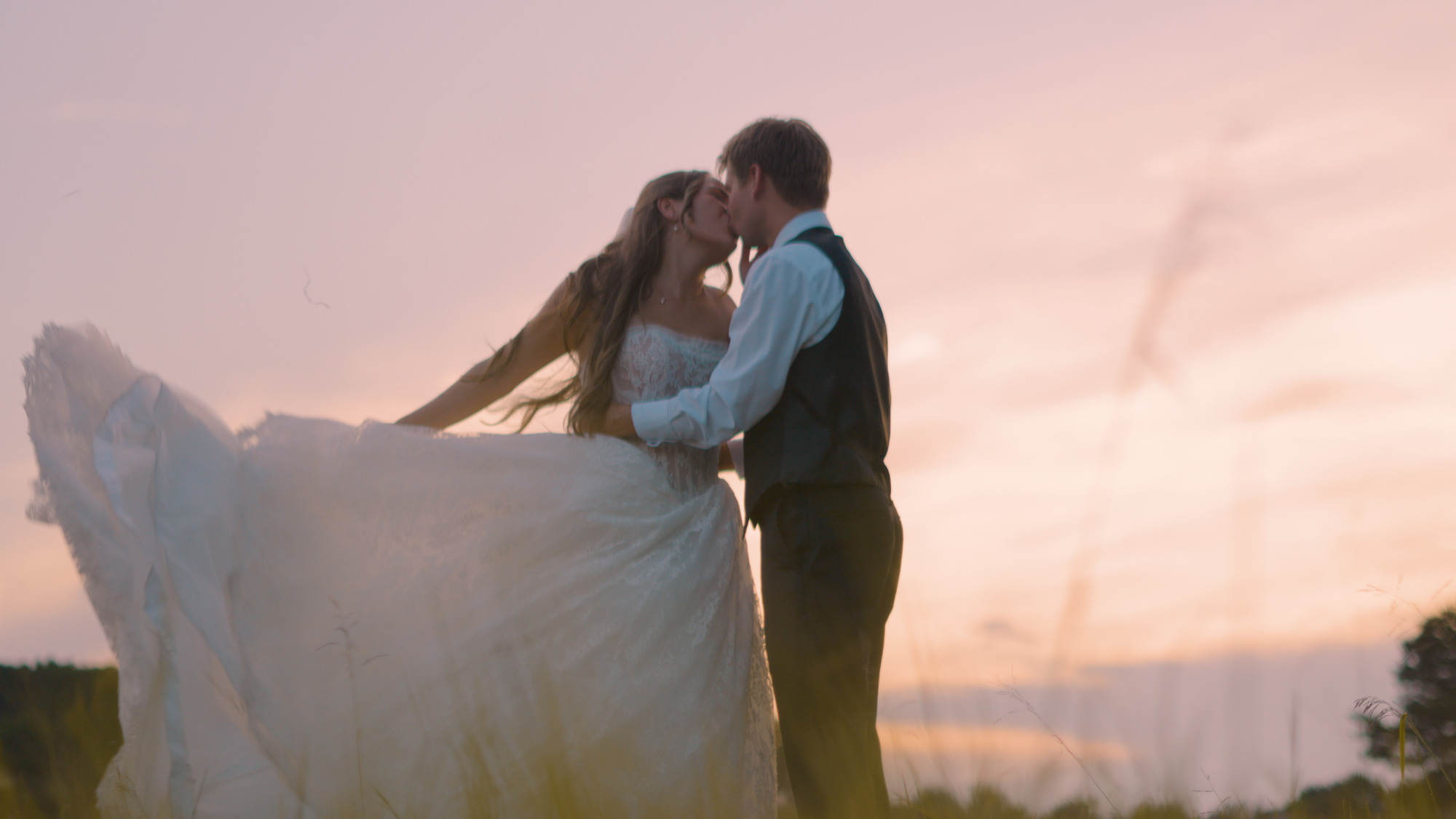 Melyiah and Austin kissing at sunset as her wedding dress flows in the wind at The Grove at Defoor Farms in Temple, Georgia